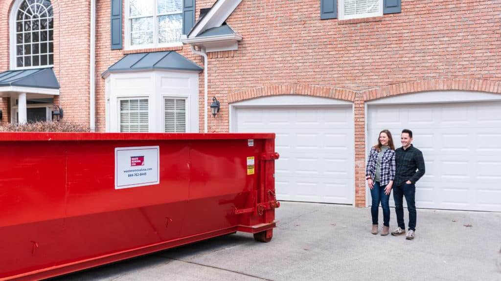 happy couple with red waste removal usa roll off dumpster